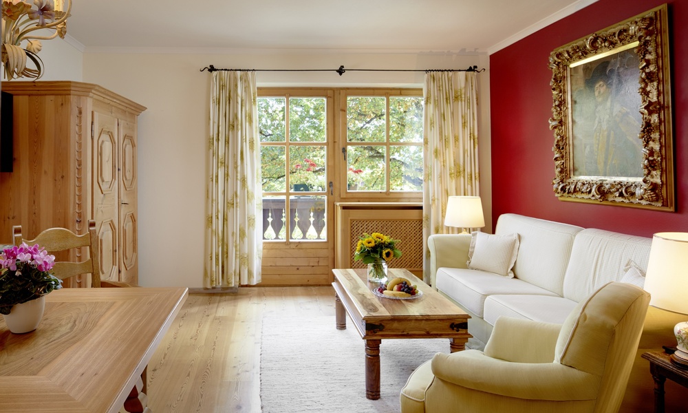 Gemütliches Wohnzimmer mit weißem Sofa, gelbem Sessel, Holztisch, großem Fenster und roter Akzentwand.