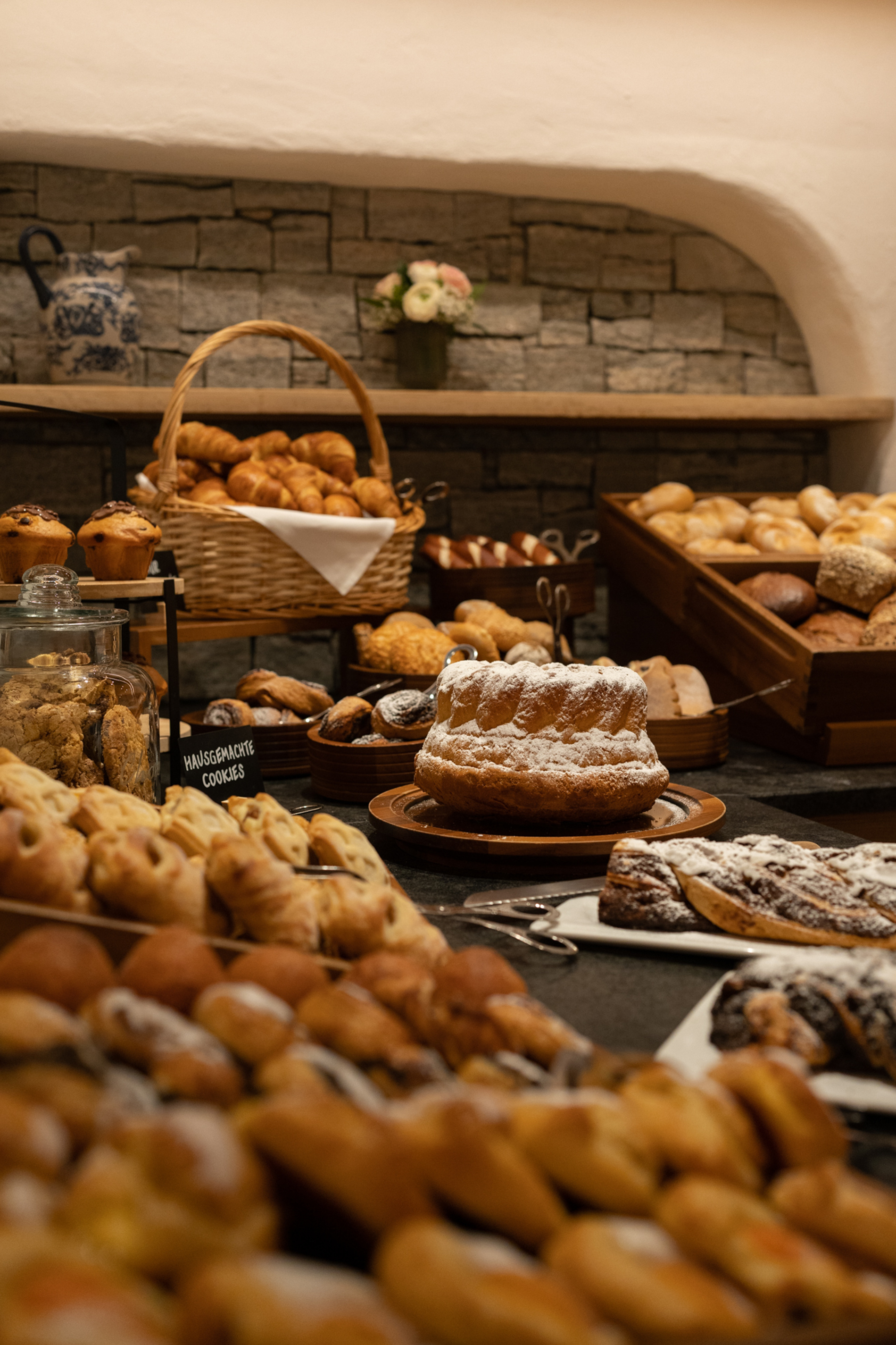Ein Sortiment von Broten, Gebäck und Kuchen auf einem rustikalen Holztisch in einer Bäckerei.