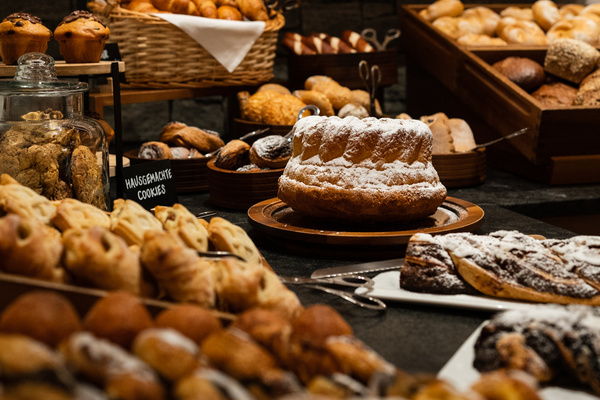 Eine Auslage mit verschiedenen Backwaren, Kuchen und Keksen auf Tabletts und in Körben in einer Bäckerei oder einem Buffet.
