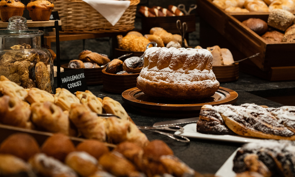 Eine Auslage mit verschiedenen Backwaren, Kuchen und Keksen auf Tabletts und in Körben in einer Bäckerei oder einem Buffet.