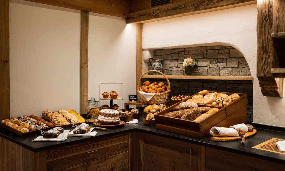 Auf einer Holztheke in einer rustikalen Bäckerei werden verschiedene Brotsorten und Backwaren angeboten.