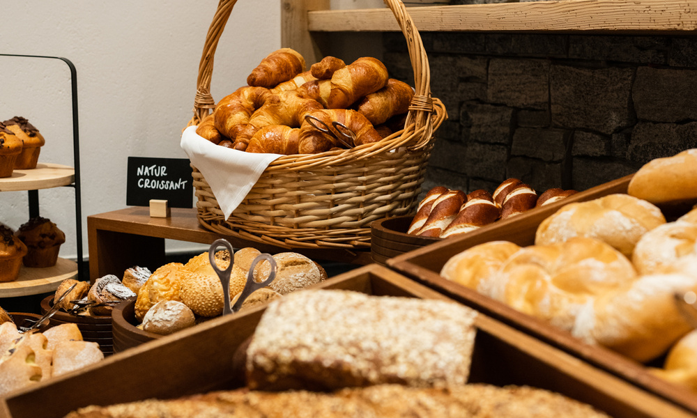 Eine Auswahl an frischem Brot und Gebäck, einschließlich Croissants, in Körben in einer Bäckerei.