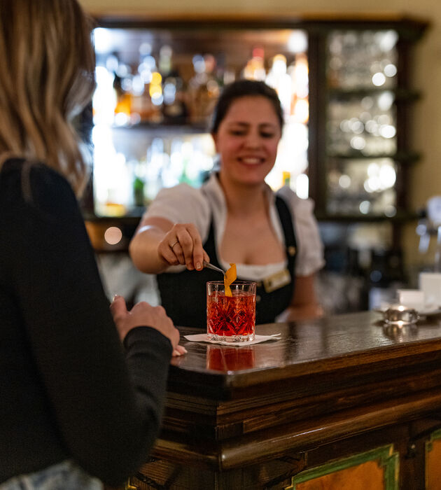 Ein Barkeeper garniert einen Cocktail für einen Kunden in einer schummrigen Bar.