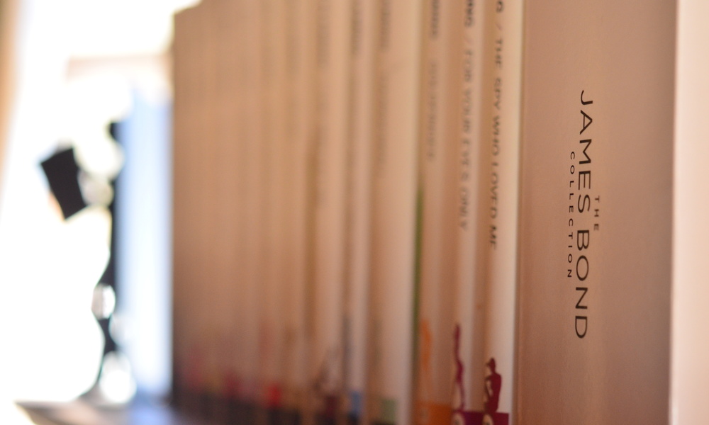 Nahaufnahme von Büchern aus der James-Bond-Sammlung, die in einem Regal aufgereiht sind, wobei die Buchrücken nach außen zeigen.