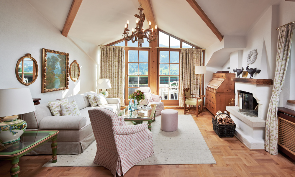 Helles, elegantes Wohnzimmer mit großen Fenstern, Holzbalken, klassischen Möbeln und einem gemütlichen Kamin.