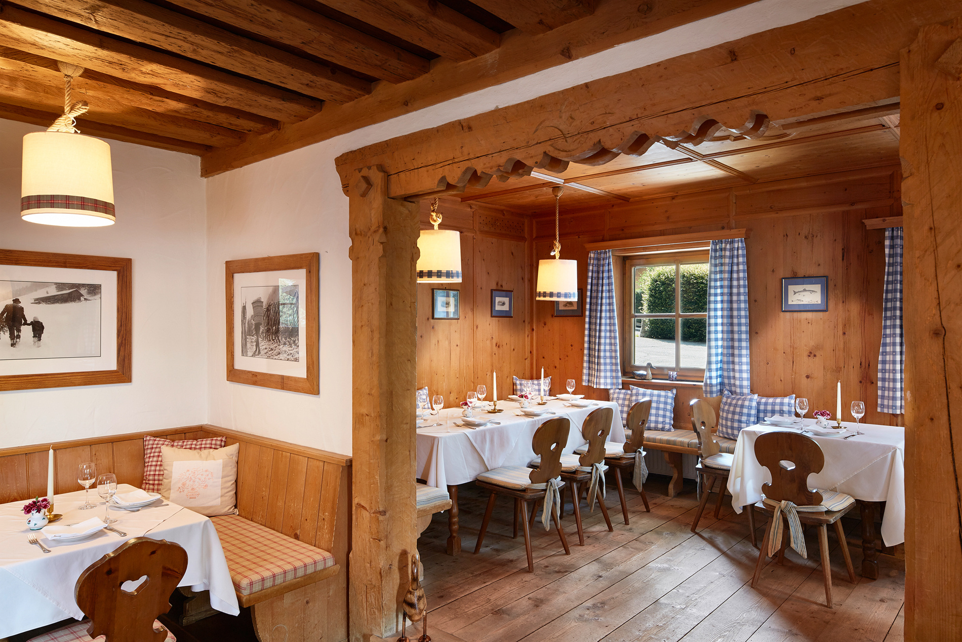 Cozy wooden restaurant with covered tables, checkered curtains and rustic decor.