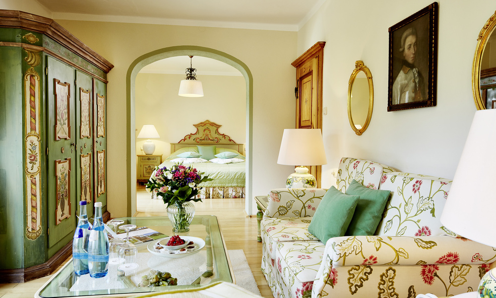 Elegantes geblümtes Wohnzimmer mit Sofa, Blumen und Getränken auf dem Tisch, das zu einem Schlafzimmer im Vintage-Stil führt.