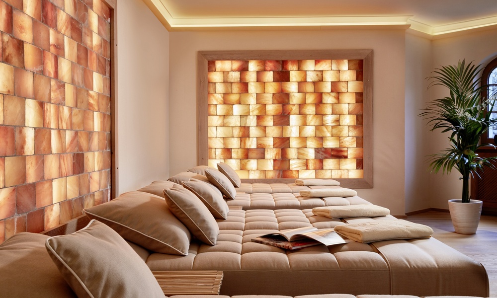 Modernes Wohnzimmer mit beigefarbenen gepolsterten Betten und leuchtenden Salzziegelwänden, mit einer Topfpflanze in der Ecke.