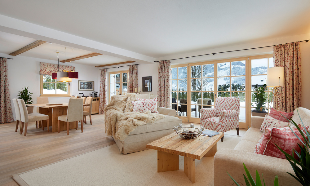 Gemütlicher Wohn- und Essbereich mit großen Fenstern, Blick auf die Berge und warmem, neutralem Mobiliar.