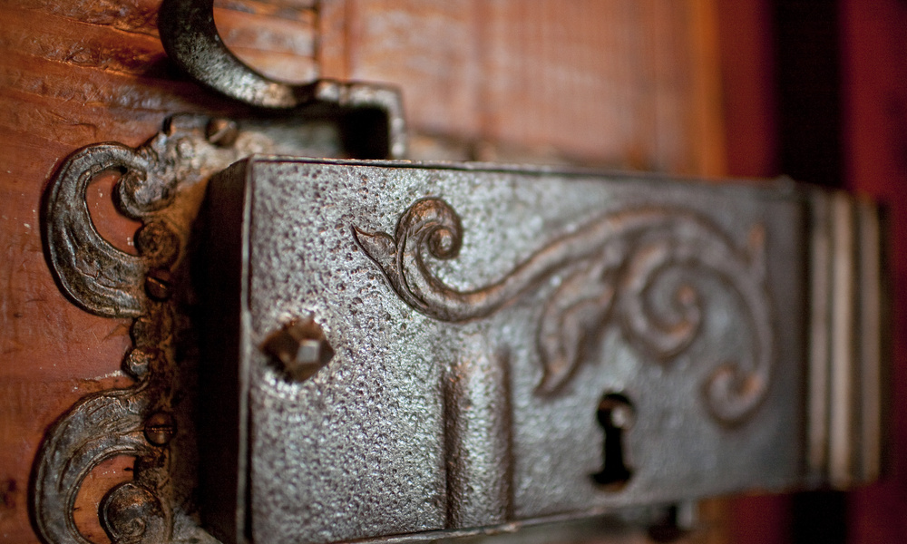 Nahaufnahme eines verschnörkelten alten Metalltürschlosses mit dekorativem Wirbelmuster und sichtbarem Schlüsselloch.