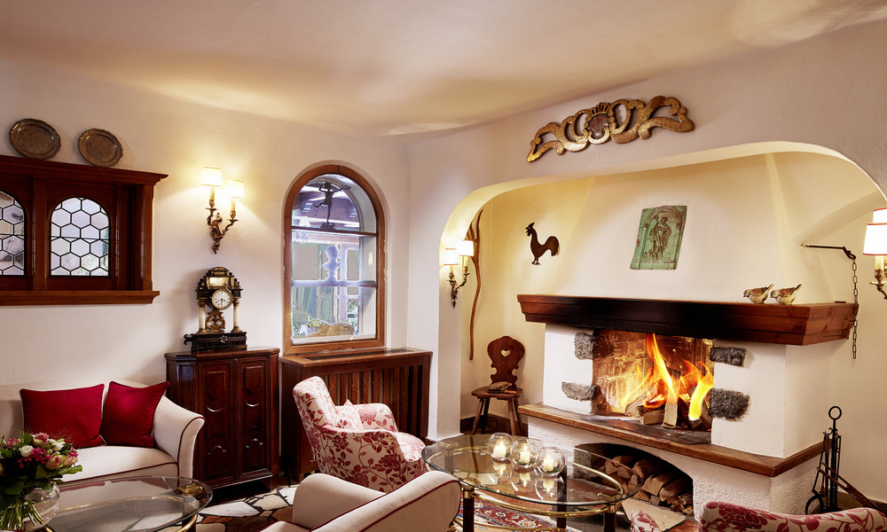 Gemütliches Wohnzimmer mit beleuchtetem Kamin, Sesseln und warmer Beleuchtung, eingerichtet im traditionellen Stil.