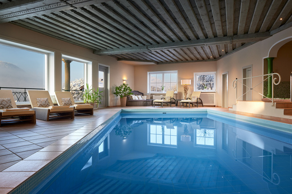Hallenbad mit Liegestühlen, Topfpflanzen und großen Fenstern, die natürliches Licht hereinlassen.