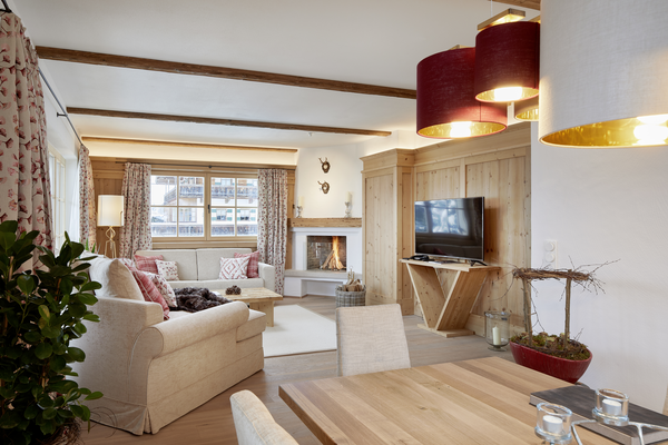 Cozy living room with beige sofas, fireplace, TV, large window and wooden accents, seen from the dining area.