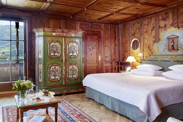 Cozy wooden bedroom with large bed, painted closet and mountain view through the balcony door.