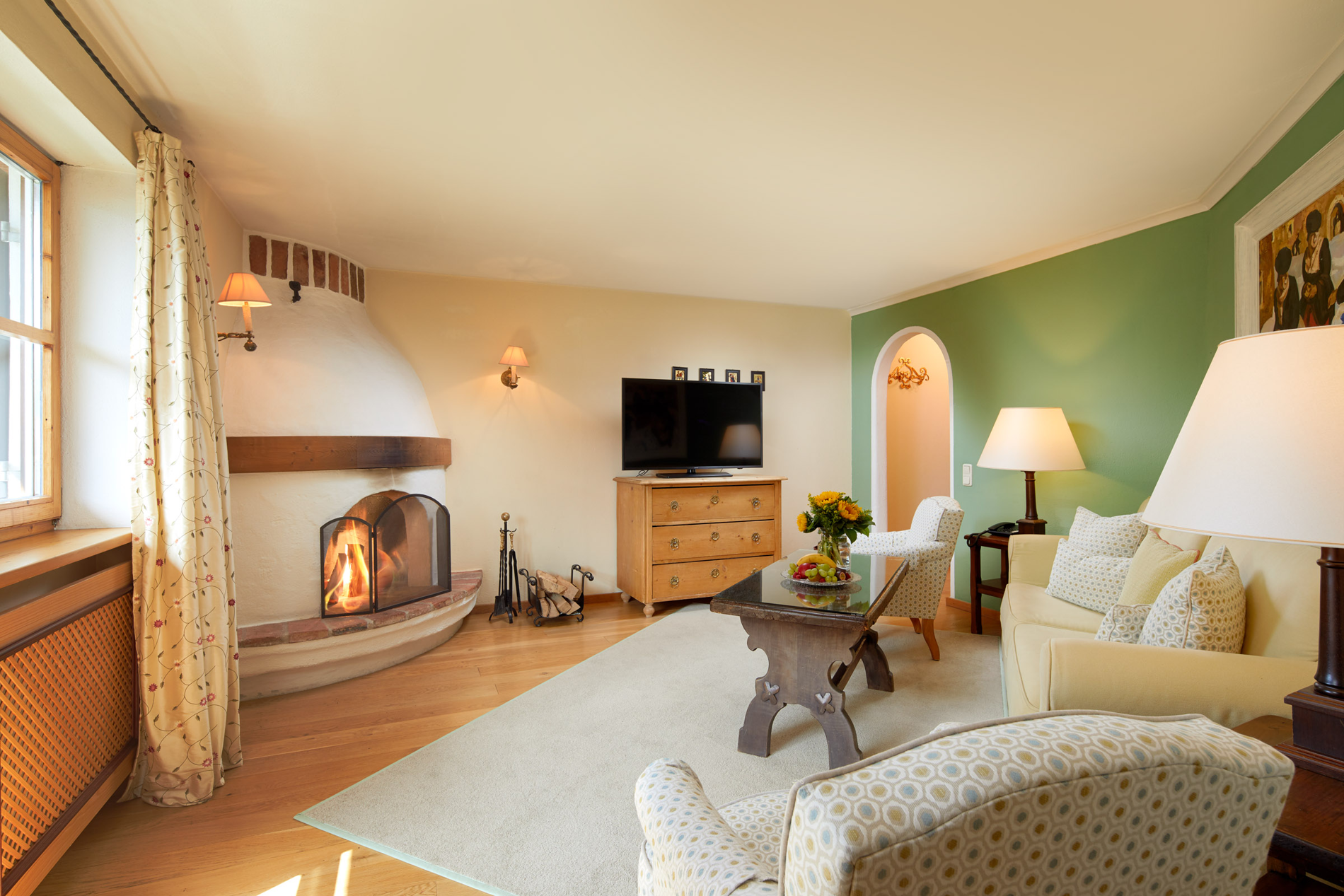 Cozy living room with fireplace, TV, sofa, armchair, coffee table and green accent wall.