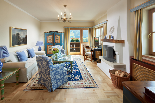 Elegant living room with blue accents, patterned carpet, fireplace, sofa and large window with mountain view.
