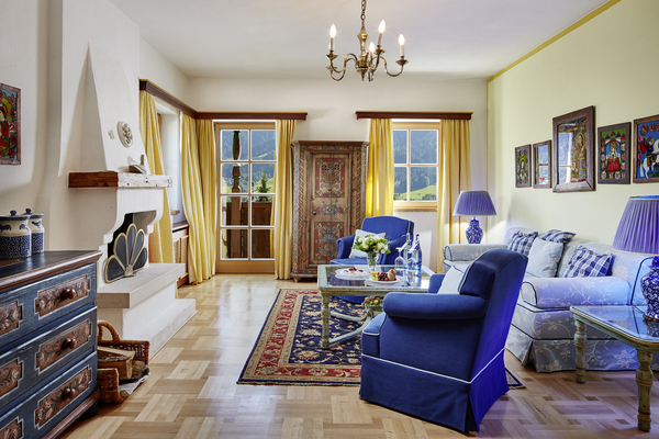 Bright living room with blue and yellow decor, patterned carpet, fireplace and large windows with mountain views.